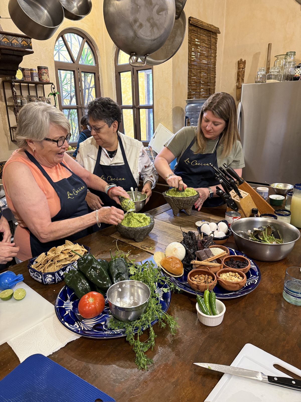 Women in La Cocina aprons making guacamole together at a cooking class