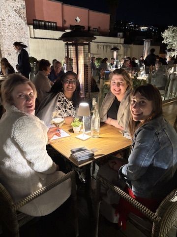 Four women at a rooftop dinner table in the evening