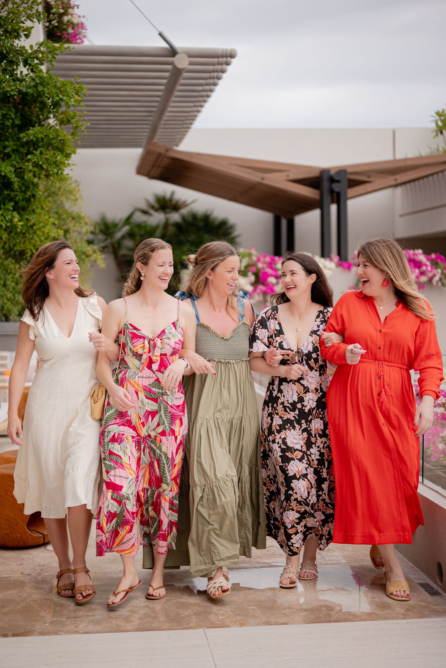 Five women walking arm in arm, laughing together